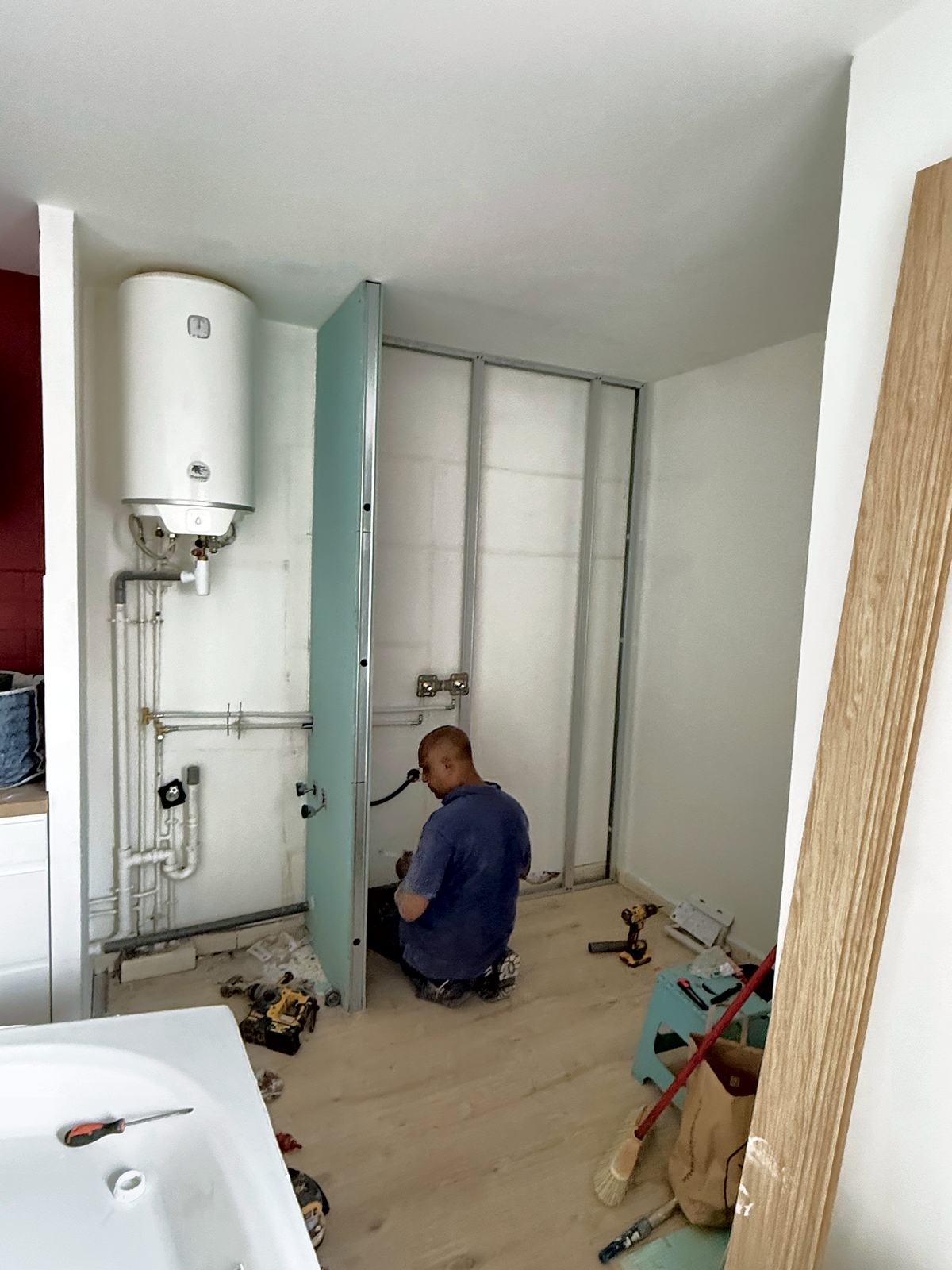 Plombier au travail derrière les cloisons d'une salle de bains en rénovation