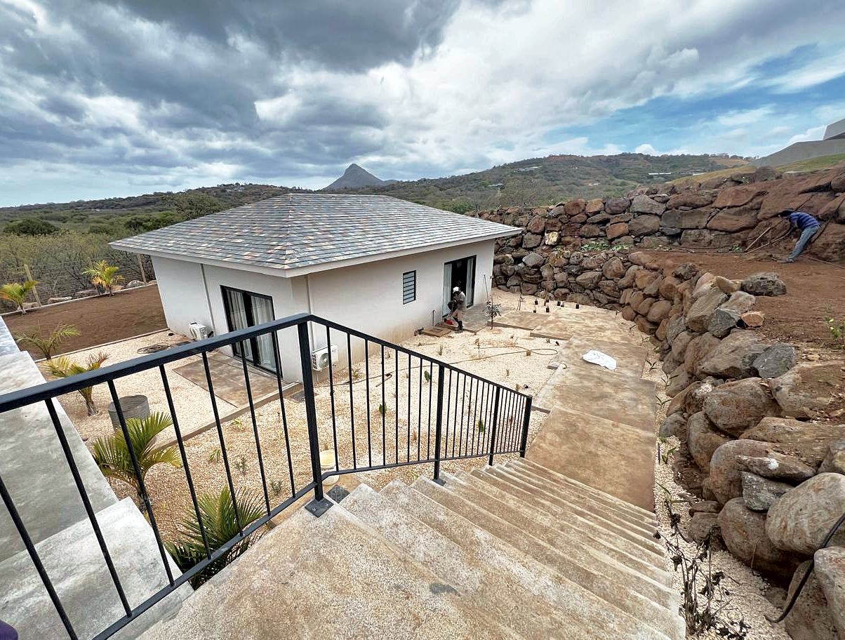Villa avec escalier en béton, garde-corps métallique et murs en pierre sèche